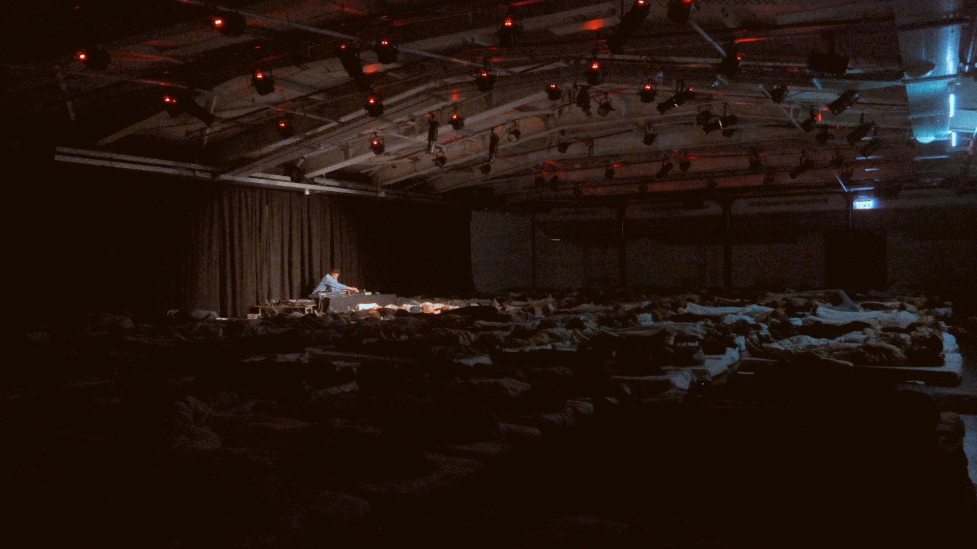 אמן על הבמה במופע מדיטציית סאונד, קהל שוכב באולם חשוך